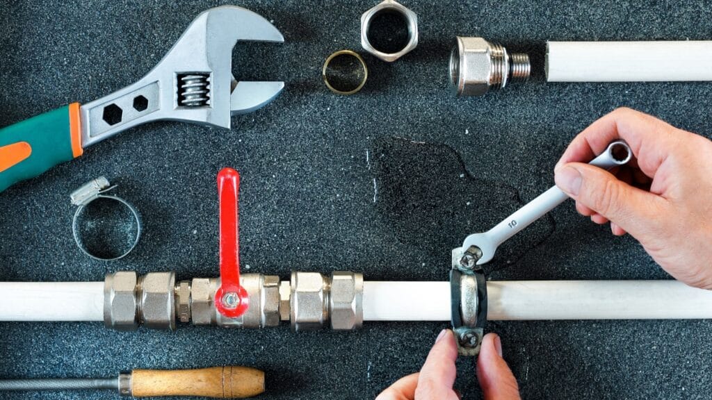 Plumber repairing a pipe valve with an adjustable wrench in Pensacola