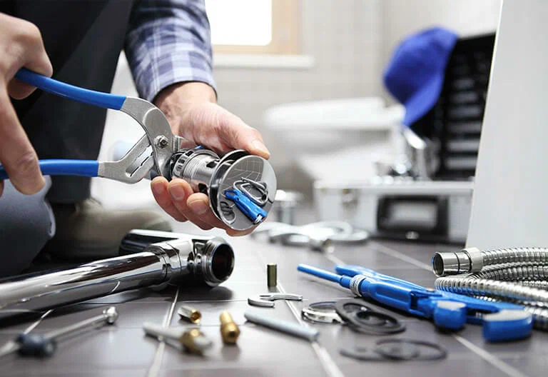 Technician repairing a plumbing fixture with professional tools in Pensacola